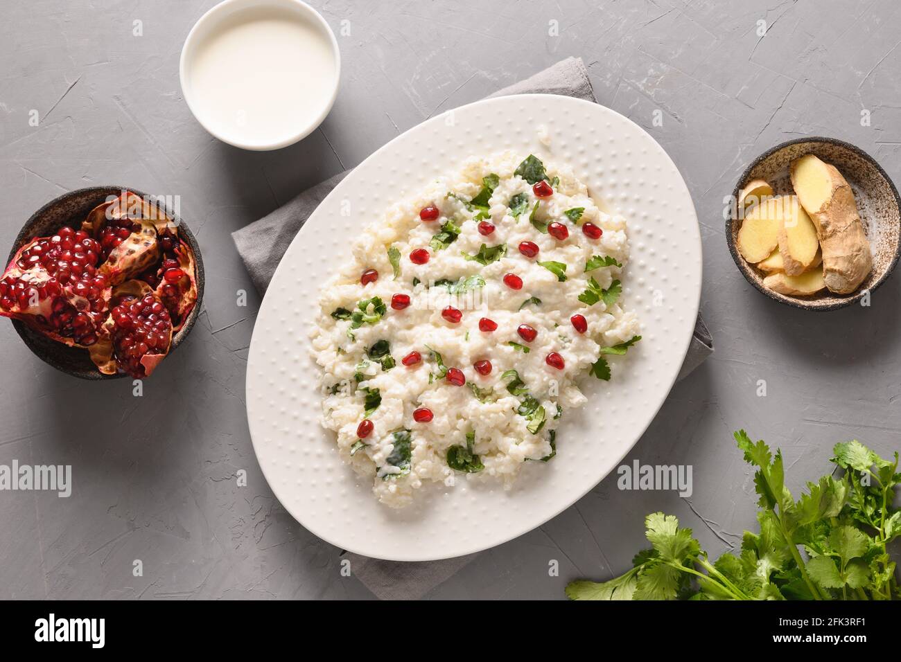 Homemade Curd Rice with pomegranate, cilantro, ginger on a grey background. Top view. Traditional Indian South cuisine Stock Photo