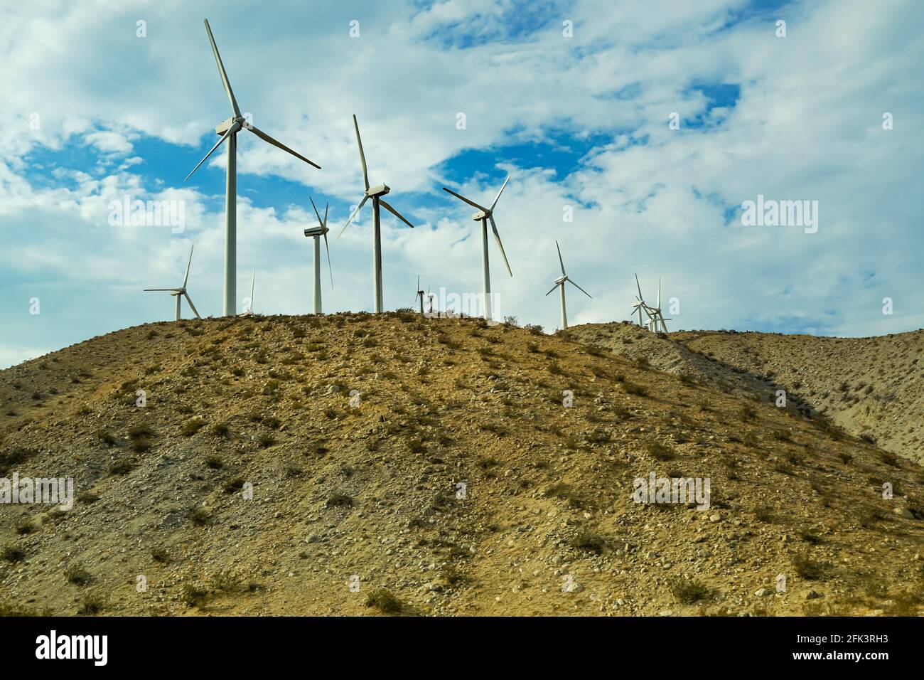 Wind turbines in a wind farm along the highway under a summer sky Stock Photo