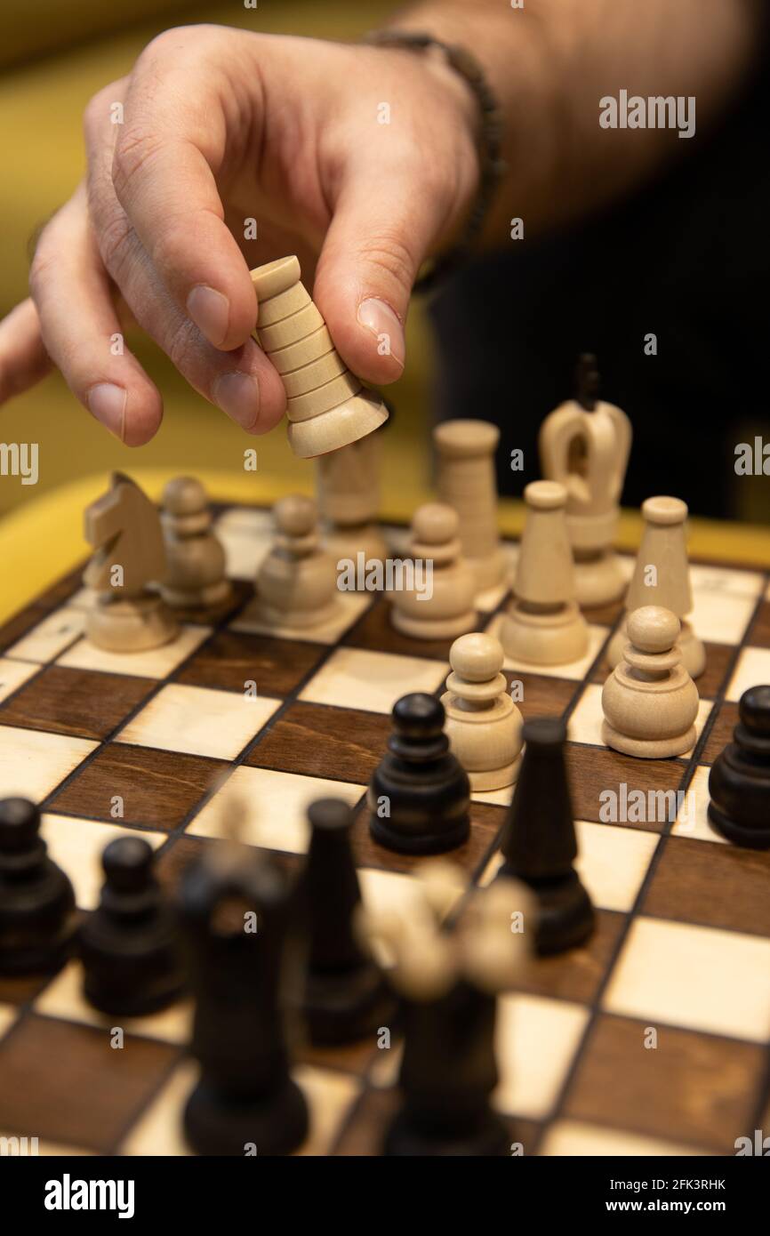 Hand taking next step on chess game. Human hand moving wooden white rook piece Stock Photo