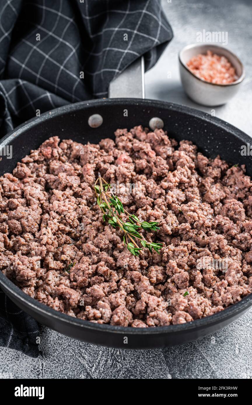Fried ground mince beef and pork meat in a pan with herbs. White