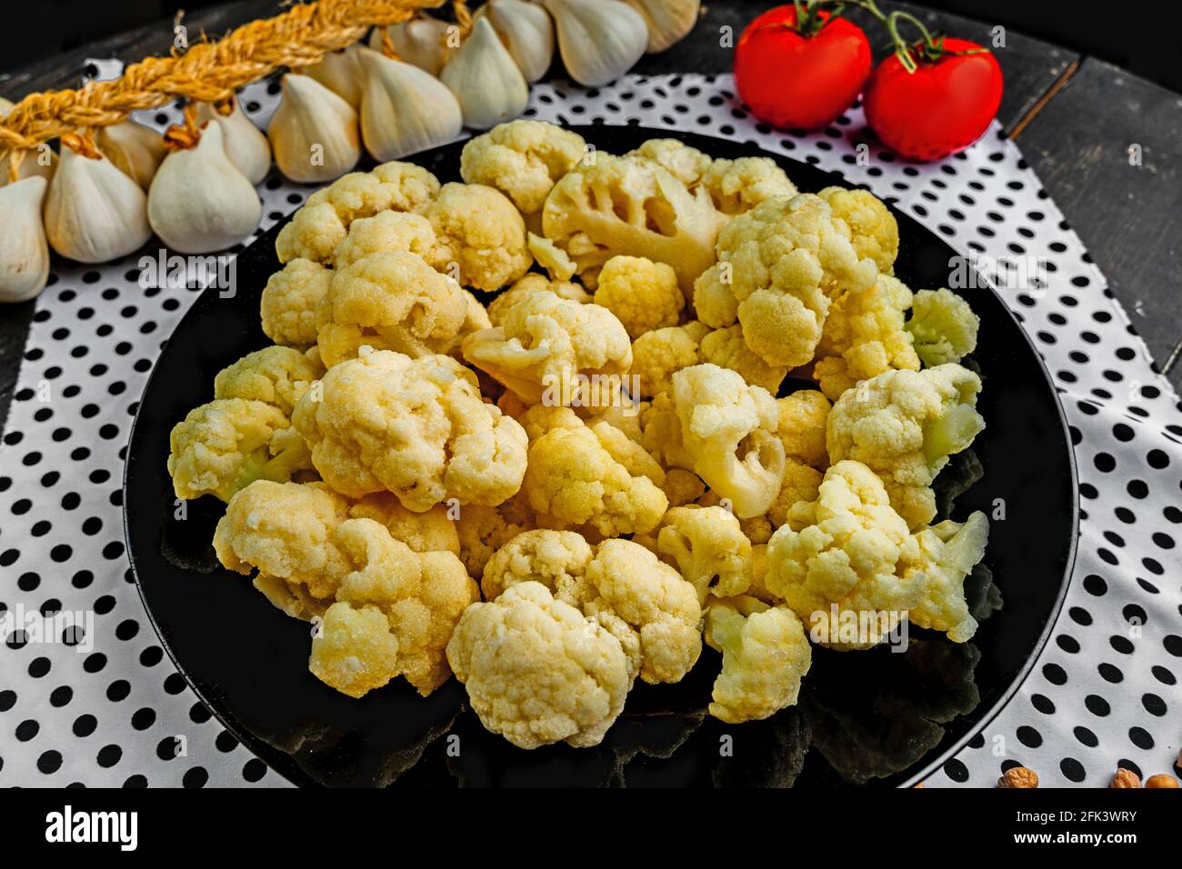 Fresh cauliflower on a black plate. Vegetables on the kitchen table.  Stock Photo