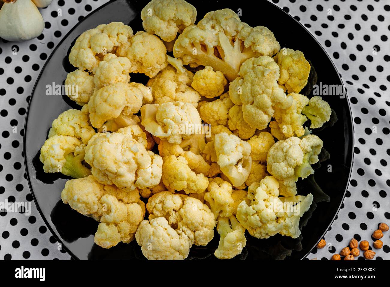 Fresh cauliflower on a black plate. Vegetables on the kitchen table.  Stock Photo