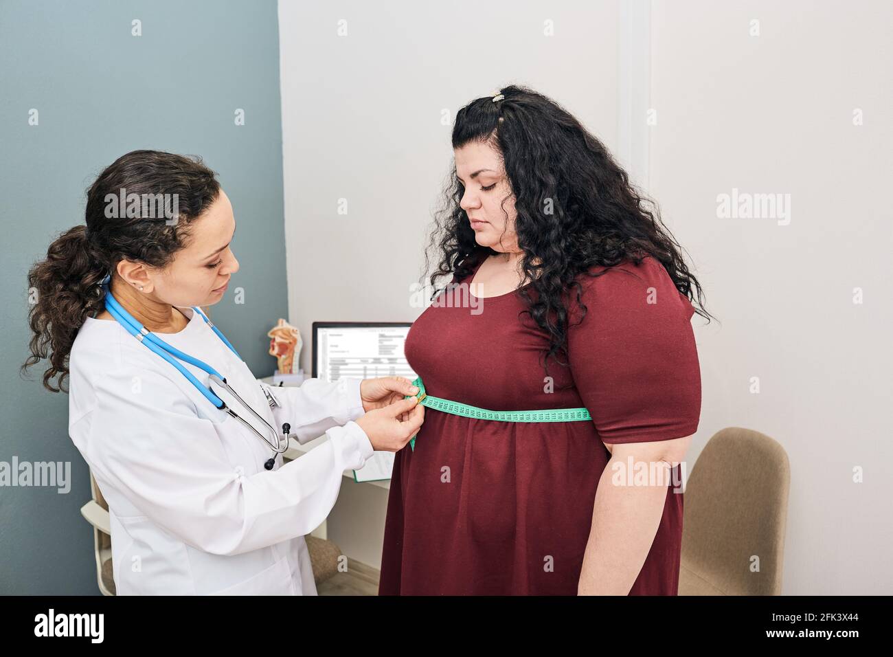 Dietitian consultation. Nutritionist inspecting a woman's waist using a