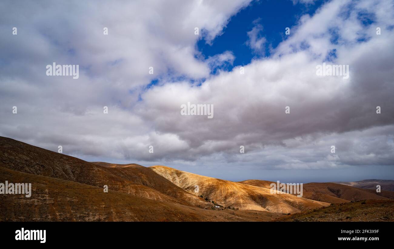 Sunlight falling through a gap in the clouds on a mountain range shot with a very low horizon Stock Photo