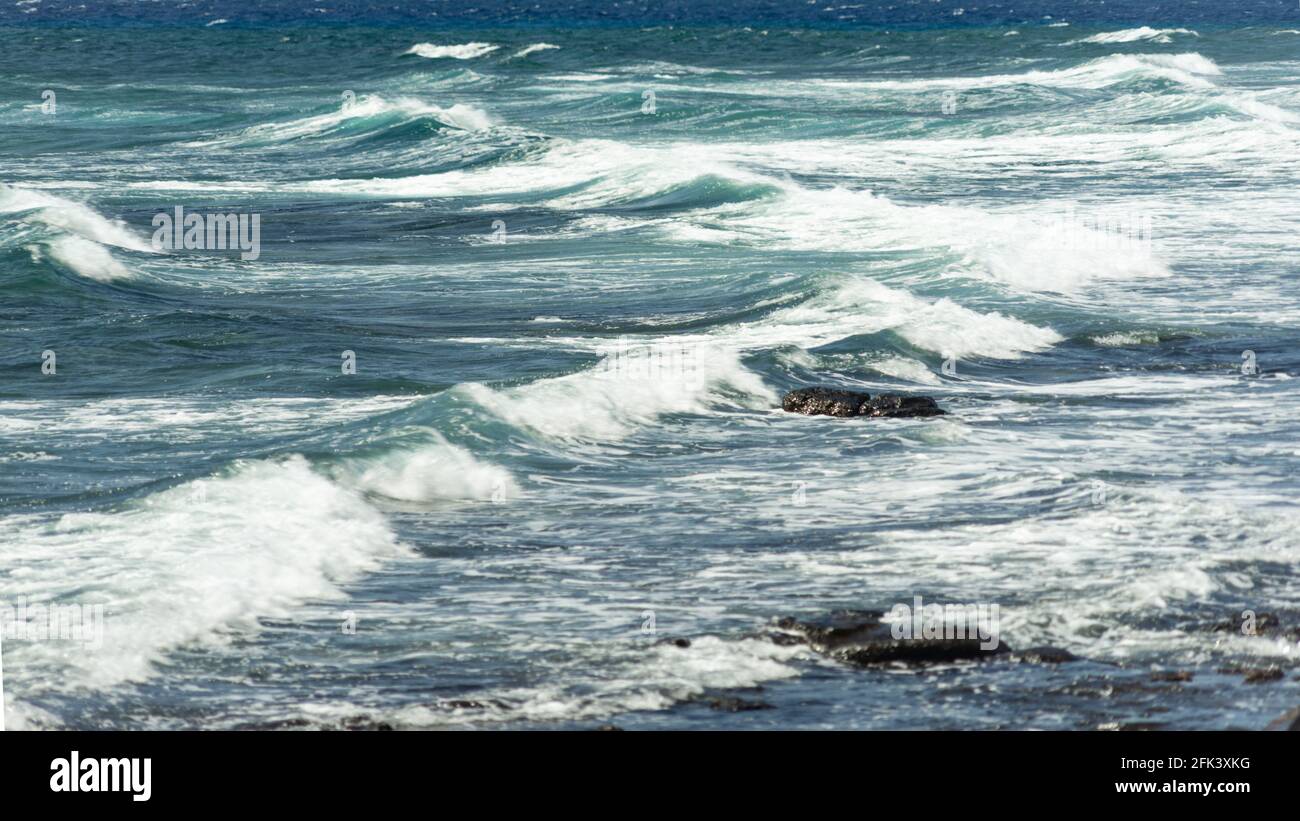 Surf coming to the beach with two rocks looking out of the shallow ...