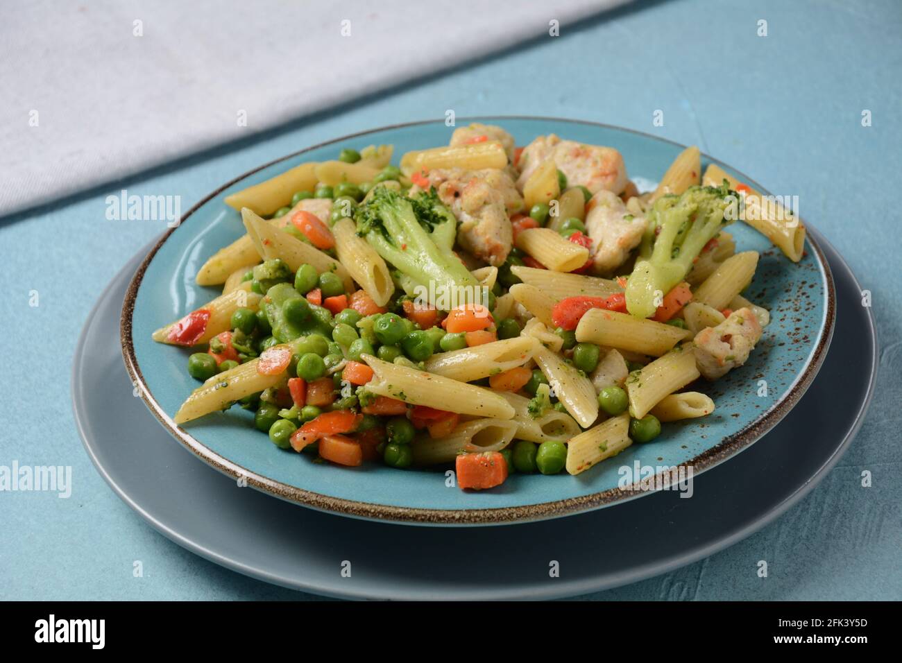 Pasta salad with baked vegetables and fried pieces of chicken breast . Penne pasta with broccoli, beans and carrots. Stock Photo