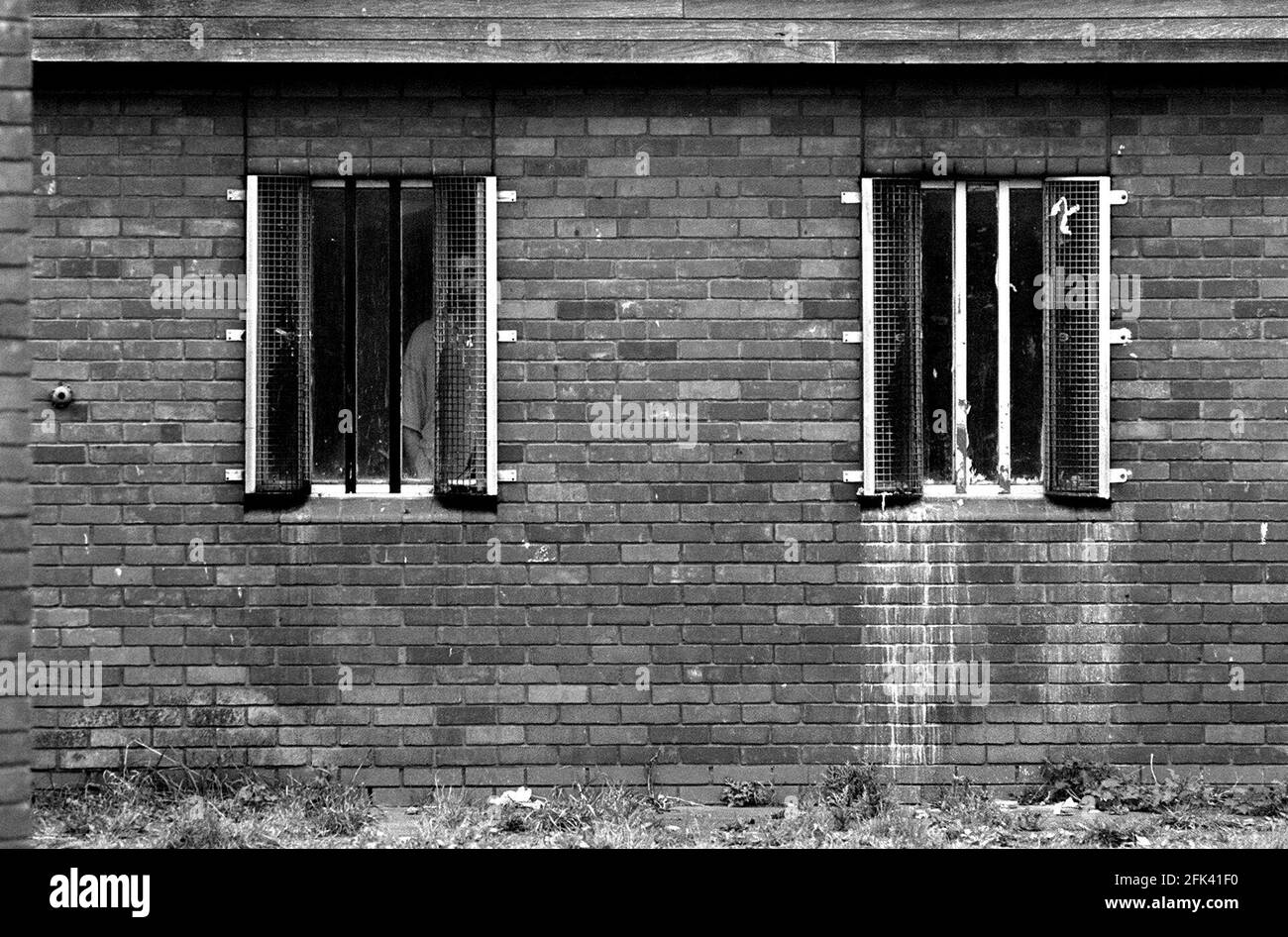 Prisoners at Remand Centre Feltham March 1999A prisoner looking out of a window of one of the house blocks at HM Young Offenders Institution and Remand Centre Feltham Richard Tilt the Director General of the Prison Service visitied the institution today the day before his retirement Stock Photo