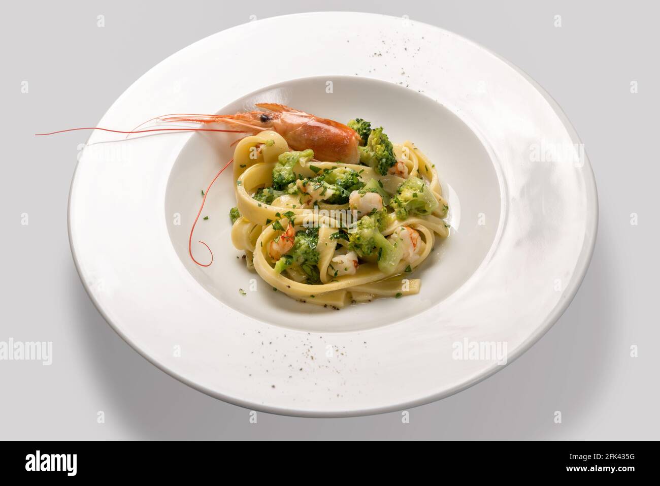 Pasta tagliatelle with prawns, prawns and broccoli in white plate isolated on light gray background Stock Photo