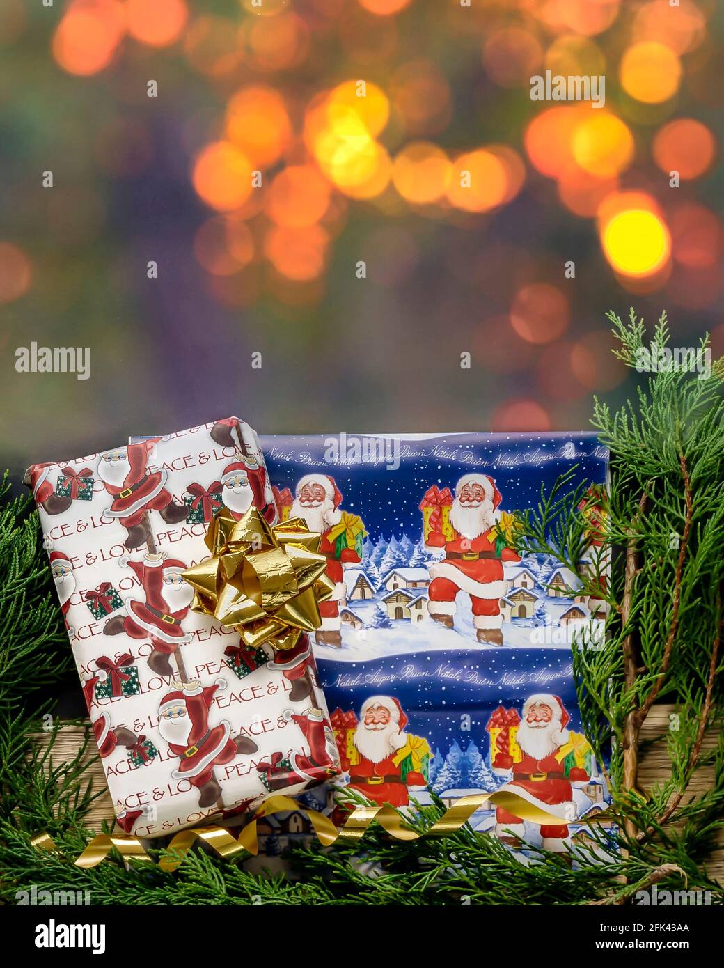 Wrapped Christmas presents near conifer branches with golden fairy lights bokeh background Stock Photo