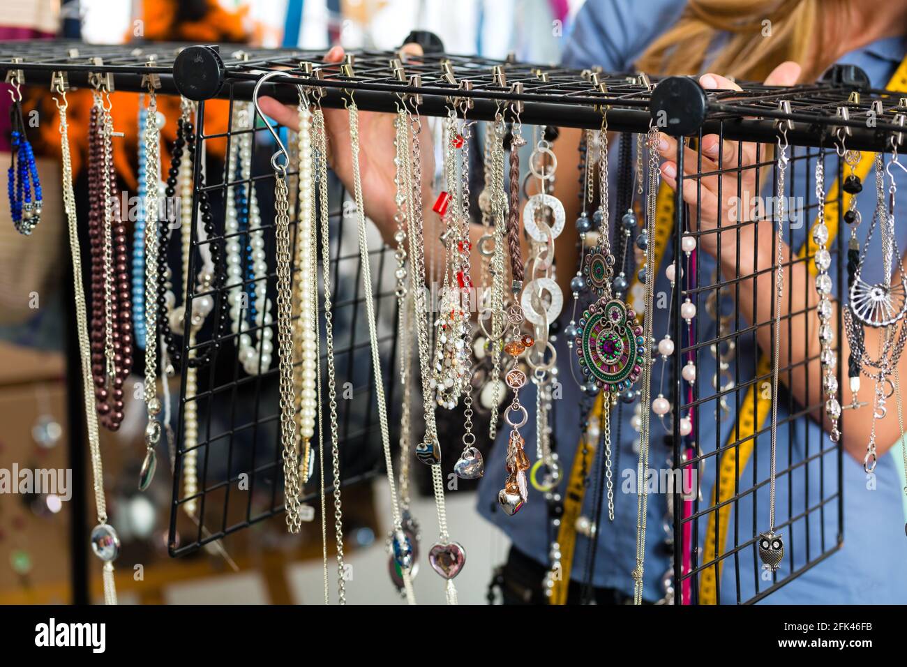 Freelance - jewelry designer working on a draft, different pieces of jewelry hanging in front Stock Photo
