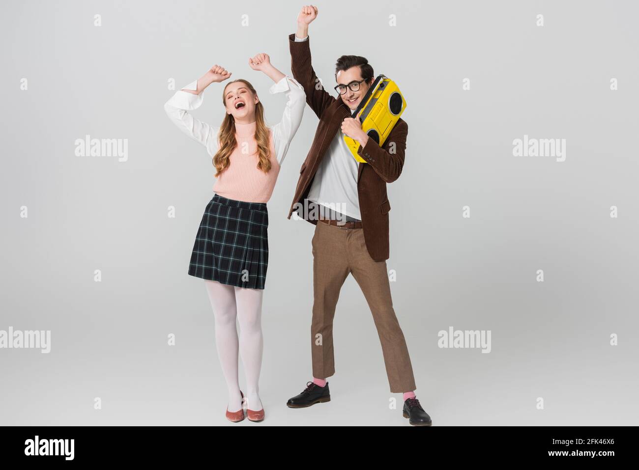 cheerful man holding vintage boombox while dancing with excited woman on grey Stock Photo