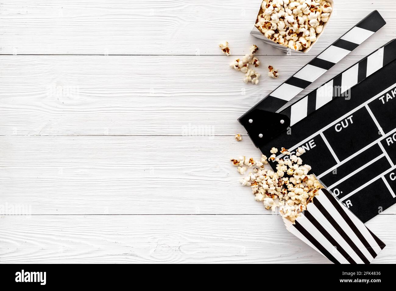 Popcorn with clapperboard and movie film reel. Cinema background Stock