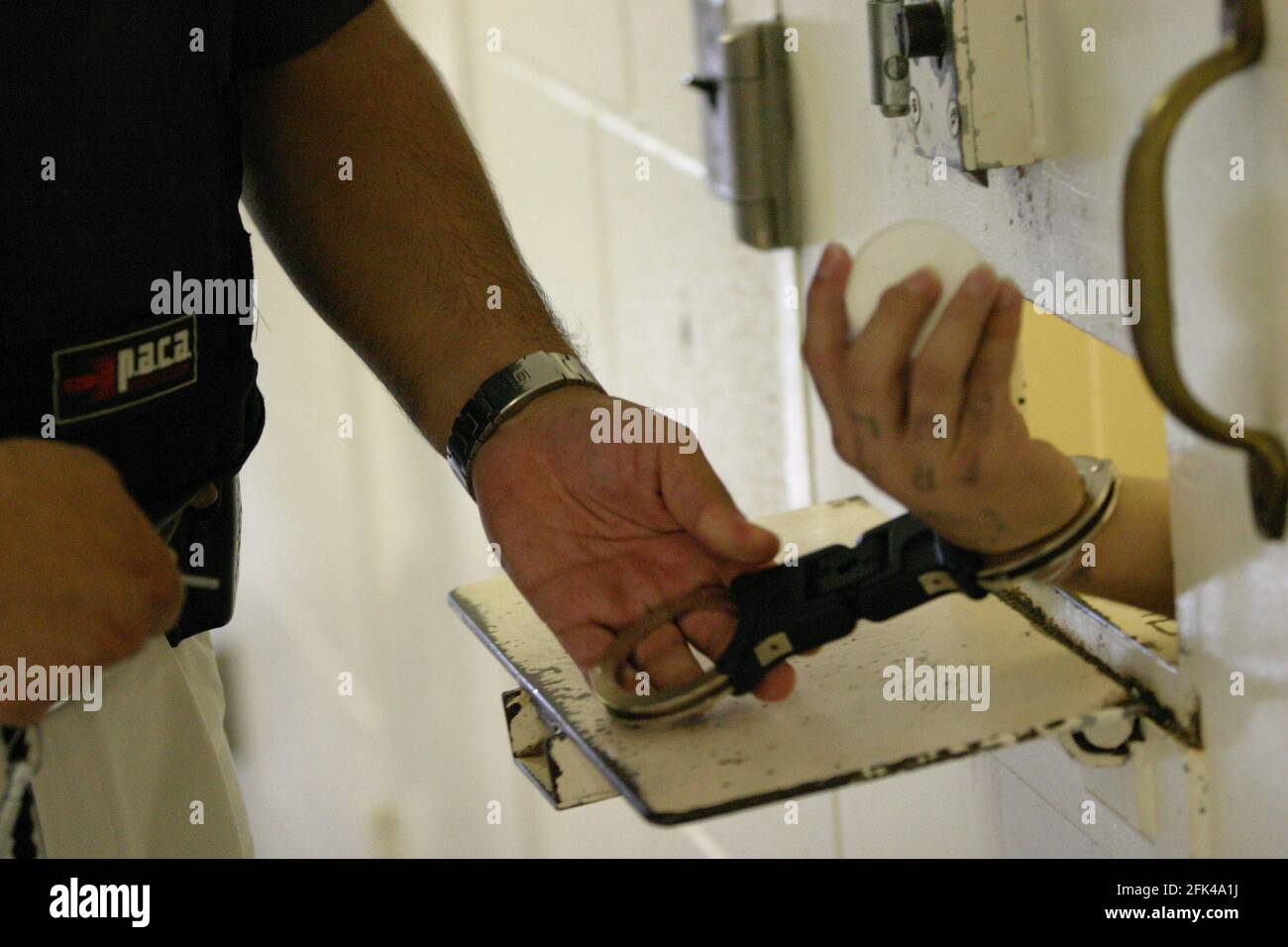 STOCKTON, UNITED STATES - Jul 27, 2004: Inmate cuffed at the cell door in a maximum-security  correctional facility in Stockton, California Stock Photo
