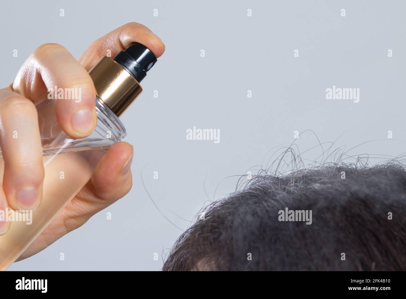 The woman puts on her hair a tonic of hydrolyte from a bottle. Hair care at home, dry dehydrated hair. Stock Photo