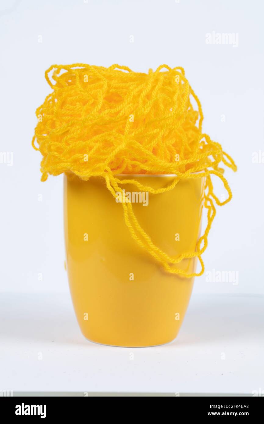 A large yellow mug with knitted threads. Stock Photo
