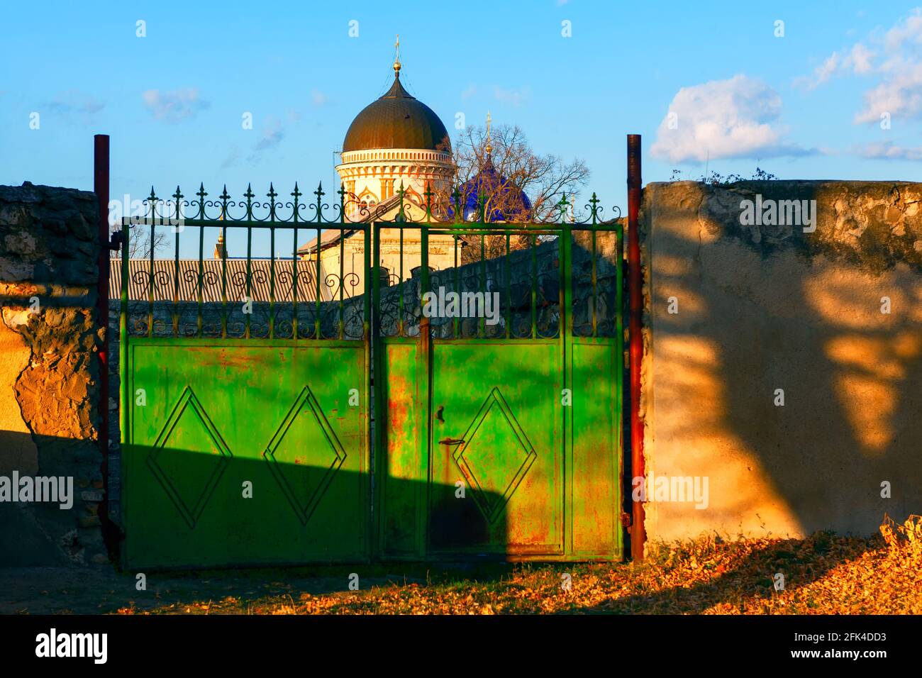Gate into the yard of the church . View of church cupola over the fence