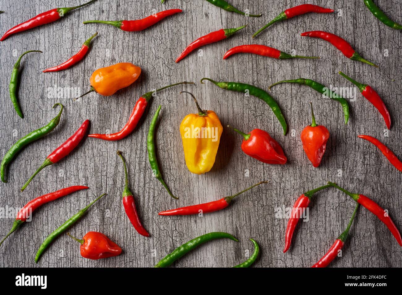 high angle view of an assortment of different chili peppers on a gray rustic wooden table Stock Photo