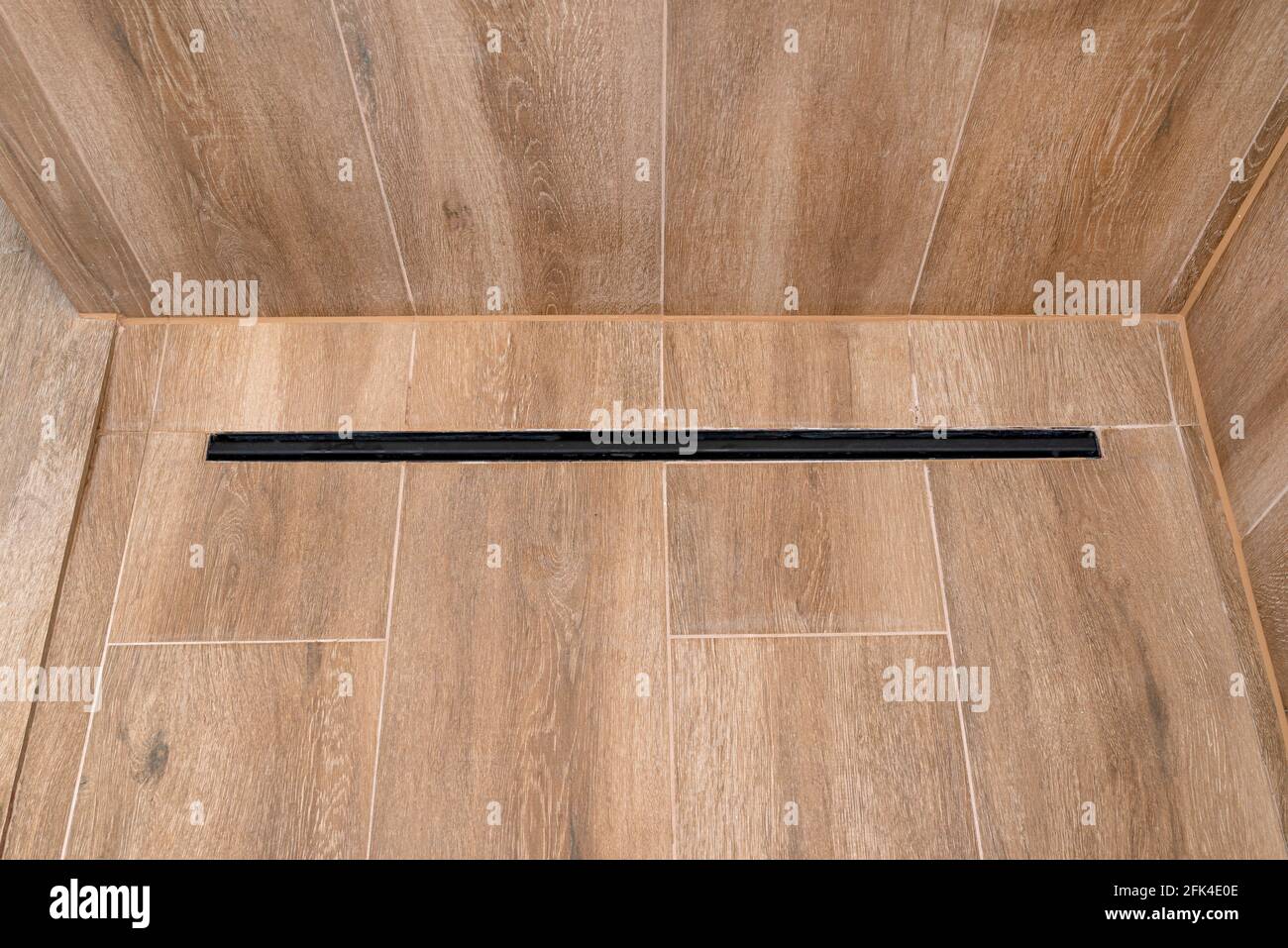 Modern black linear drain in a bathroom lined with ceramic tiles ...