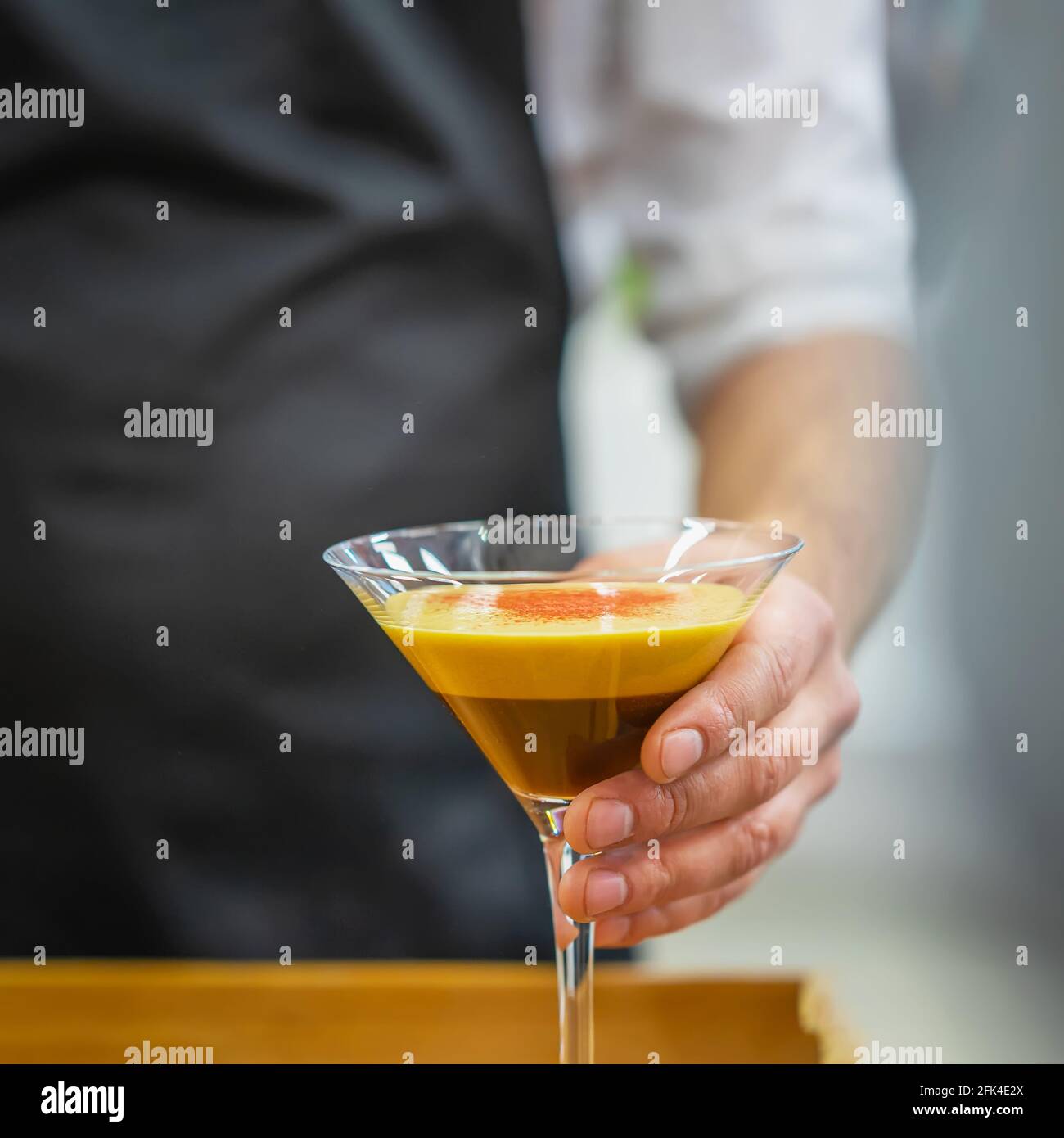 Hand of Barista holding glass of espresso coffee cocktail closeup. Alcoholic and nonalcoholic