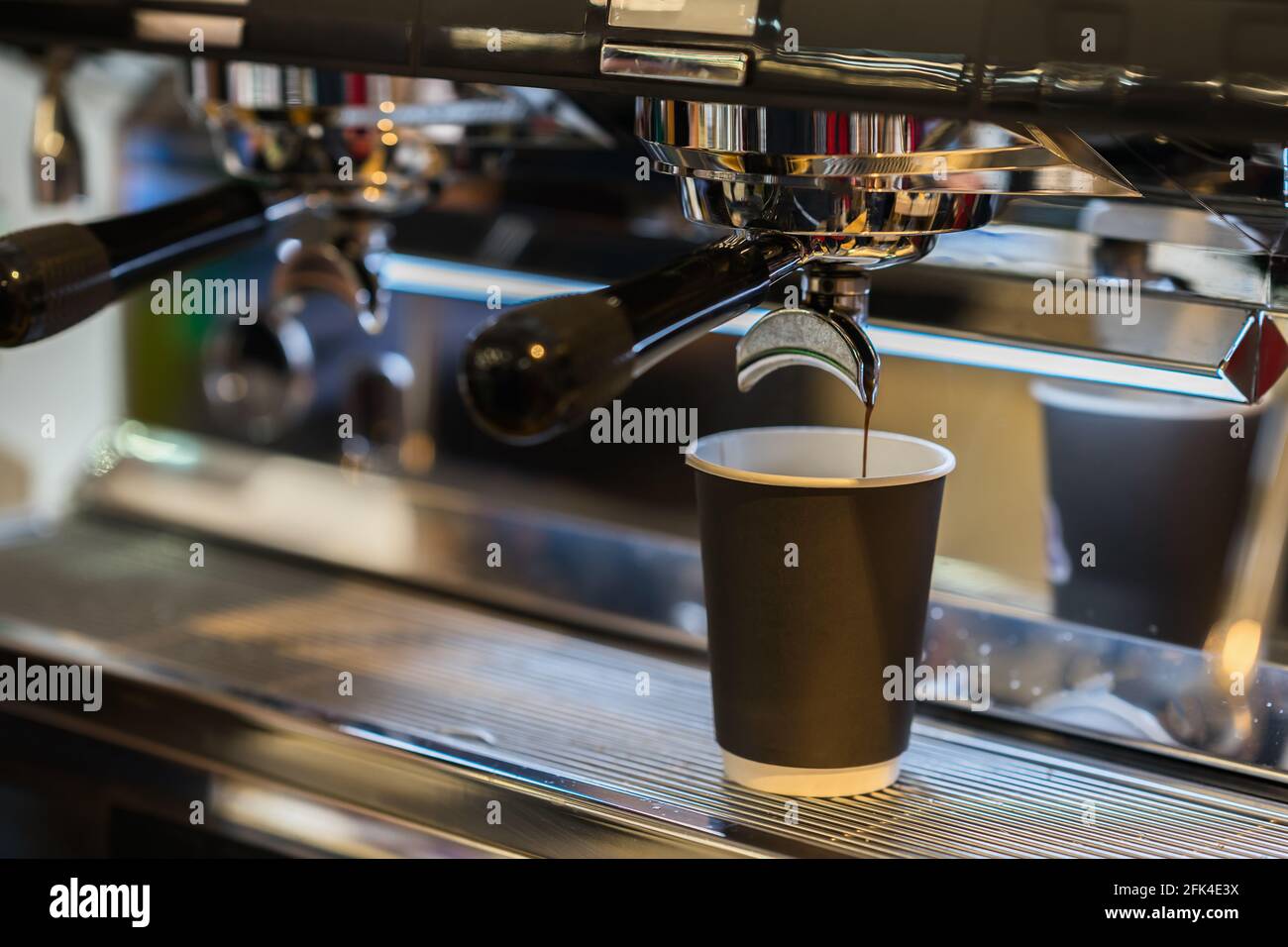 Espresso pouring from coffee machine into disposable paper cup of ...