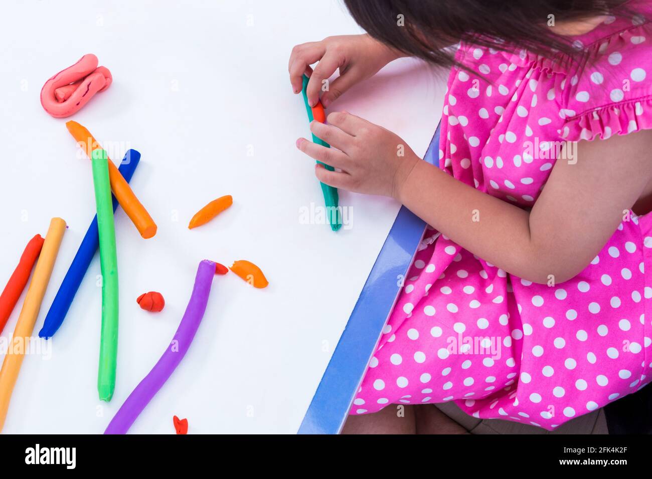 Little girl creating toys from play dough. Child moulding modeling clay. Strengthen the imagination of child Stock Photo