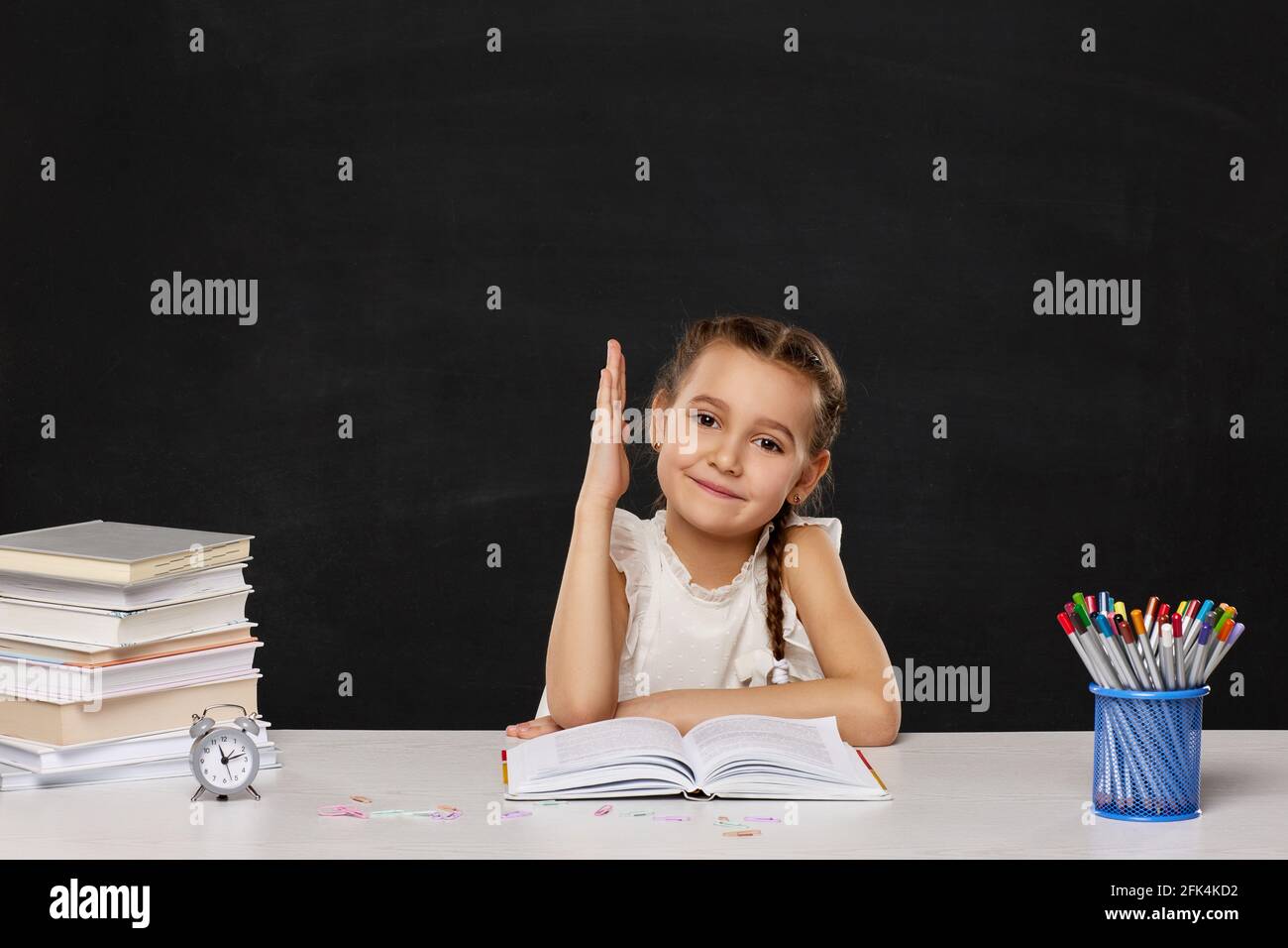 happy schoolgirl raised her hand up while sitting at table Stock Photo ...