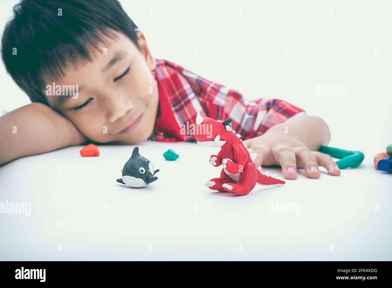Asian handsome child sleeping with his works from clay, on white background. Strengthen the imagination of child. Vintage picture style. Selective Foc Stock Photo