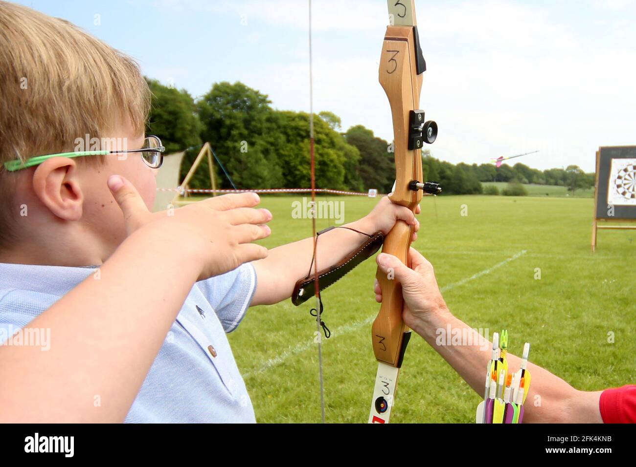 Ayr Archery Club held an open day 'Come and try Archery ' at the J.Mowatt playing fields Doonside, Ayr 5yr old Lewis Flynn receives instruction from Willie Roney as he lets his arrow go Stock Photo
