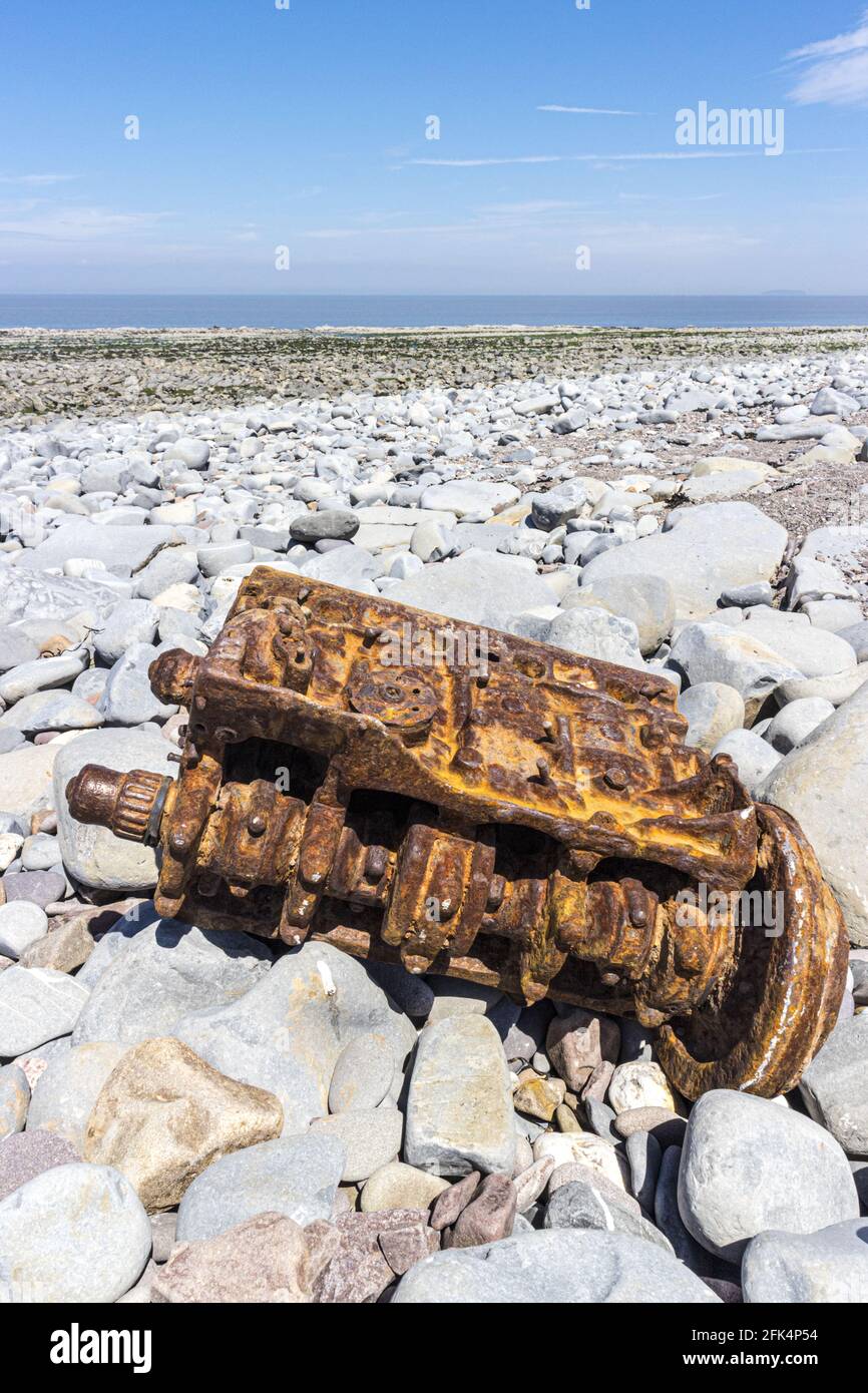 The rusty remains of a vehicle engine on the stony beach at Kilve, Somerset UK Stock Photo