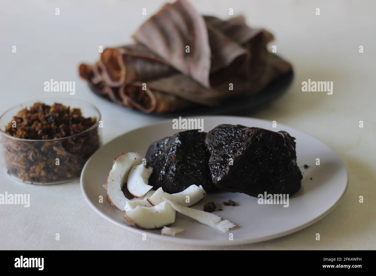 Palm jaggery and sliced coconut. A natural sweet combination. Shot on white combination. Stock Photo