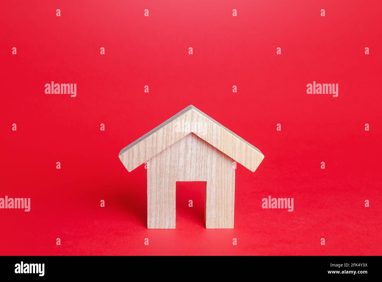 Wooden house on a red background. Buying and selling. Housing, realtor services. Mortgage loan. Renovation and home improvement. Building maintenance. Stock Photo