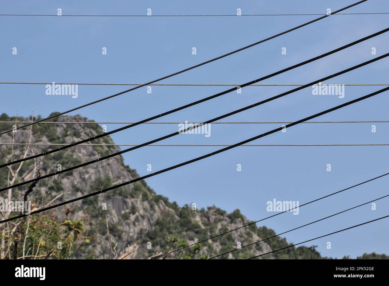 A view of messy art from modern wires and cables. A traditional natural mountain backdrop. Stock Photo