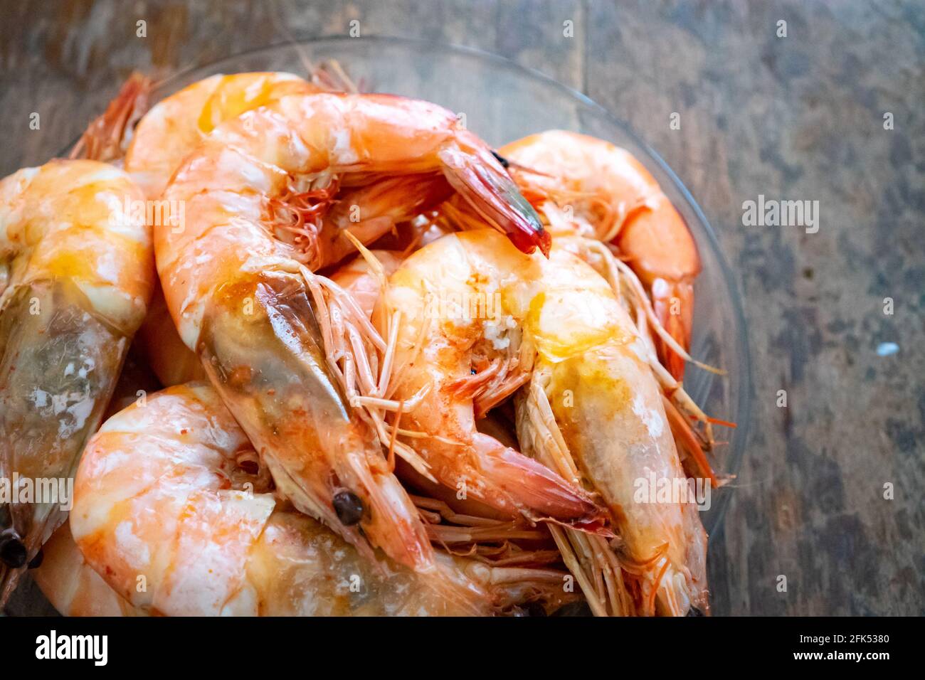 Close up to the Boiled Shrimp in the glass bowl on wooden background. Stock Photo