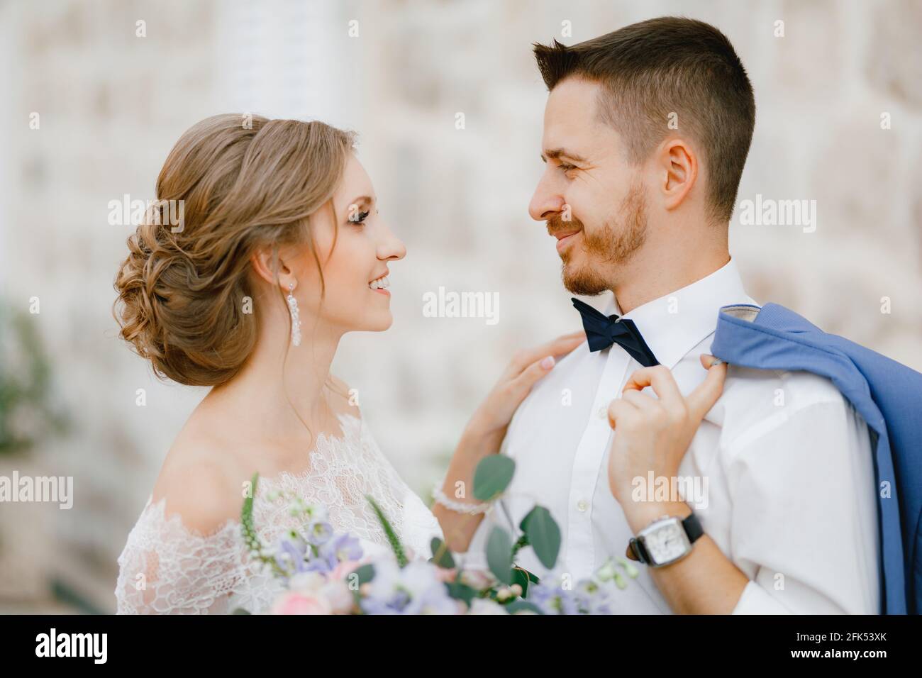 The bride and groom stand hugging near a beautiful brick house in the ...