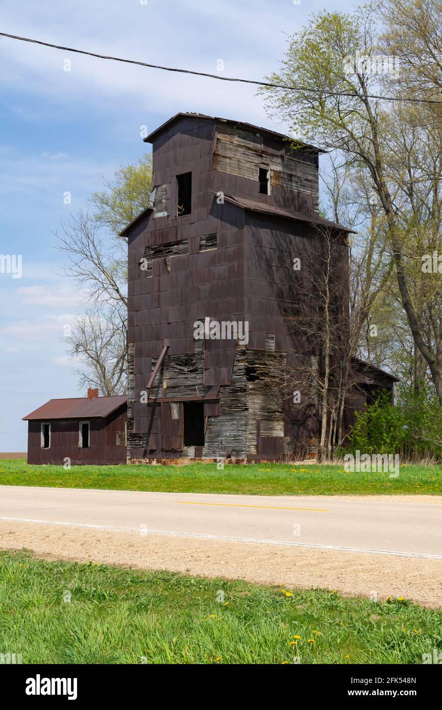 Old abandoned wooden grain elevator on county road in rural Illinois