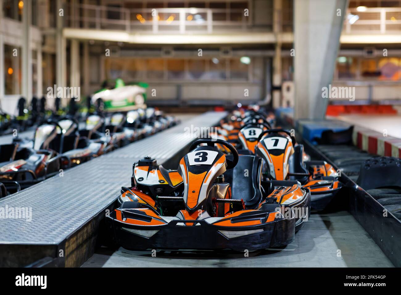 Kart cars parked one by one on indoor go-kart racing track in anticipation of drivers. Shallow focus. Stock Photo