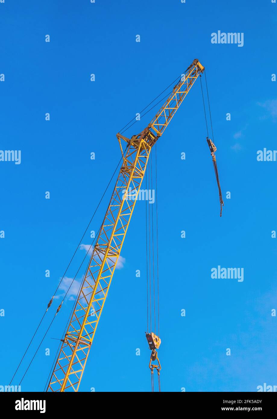 Hoisting machine industrial crane equipment against blue sky at construction site. Stock Photo