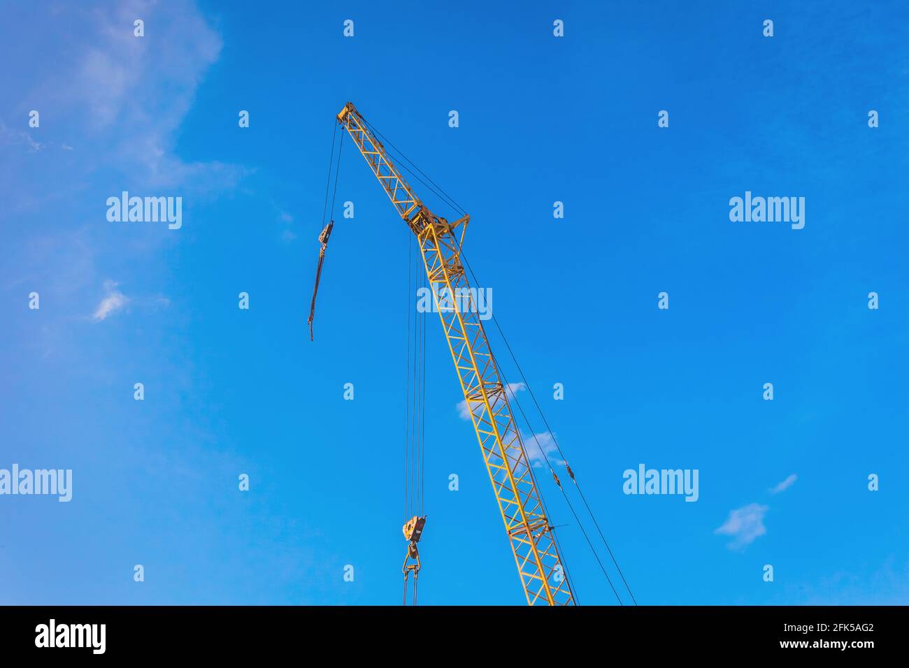 Hoisting machine industrial crane equipment against blue sky at construction site. Stock Photo