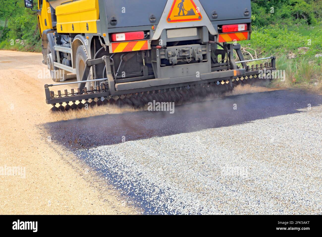 Construction of a road by trucks with aggregates and tar Stock Photo