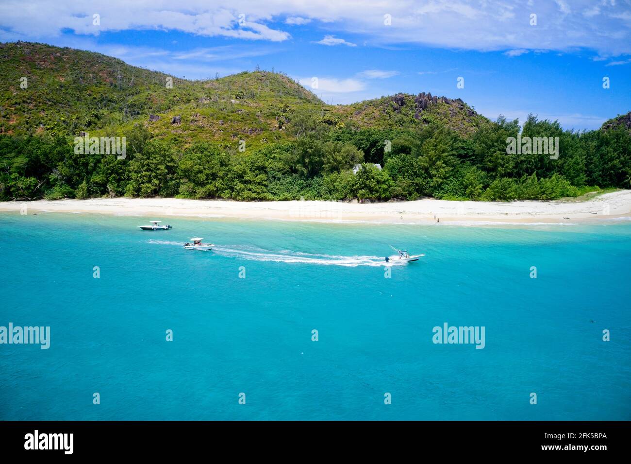 Drone field of view of speeding boat in turquoise water Curieuse Island, Seychelles. Stock Photo