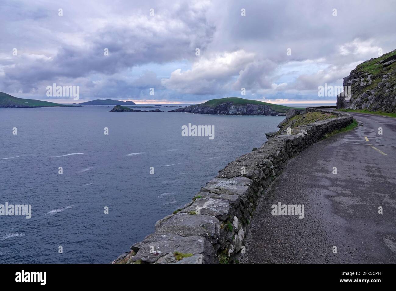The North Atlantic Ocean is viewed from the rocky coastline of Dingle Peninsula, Ireland during the evening. Stock Photo