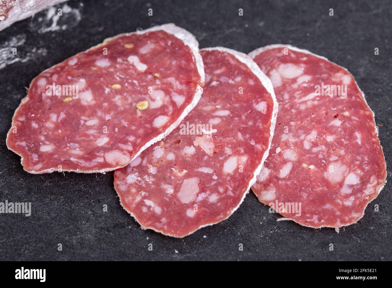 Delicious italian felino sliced salami. Macro. Located on black