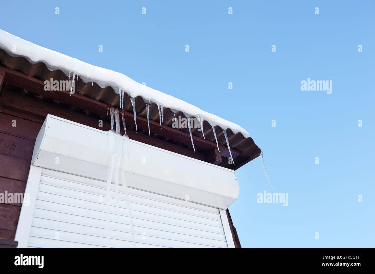 Icicles in winter. Ice stalactite hanging from the roof of building Stock Photo