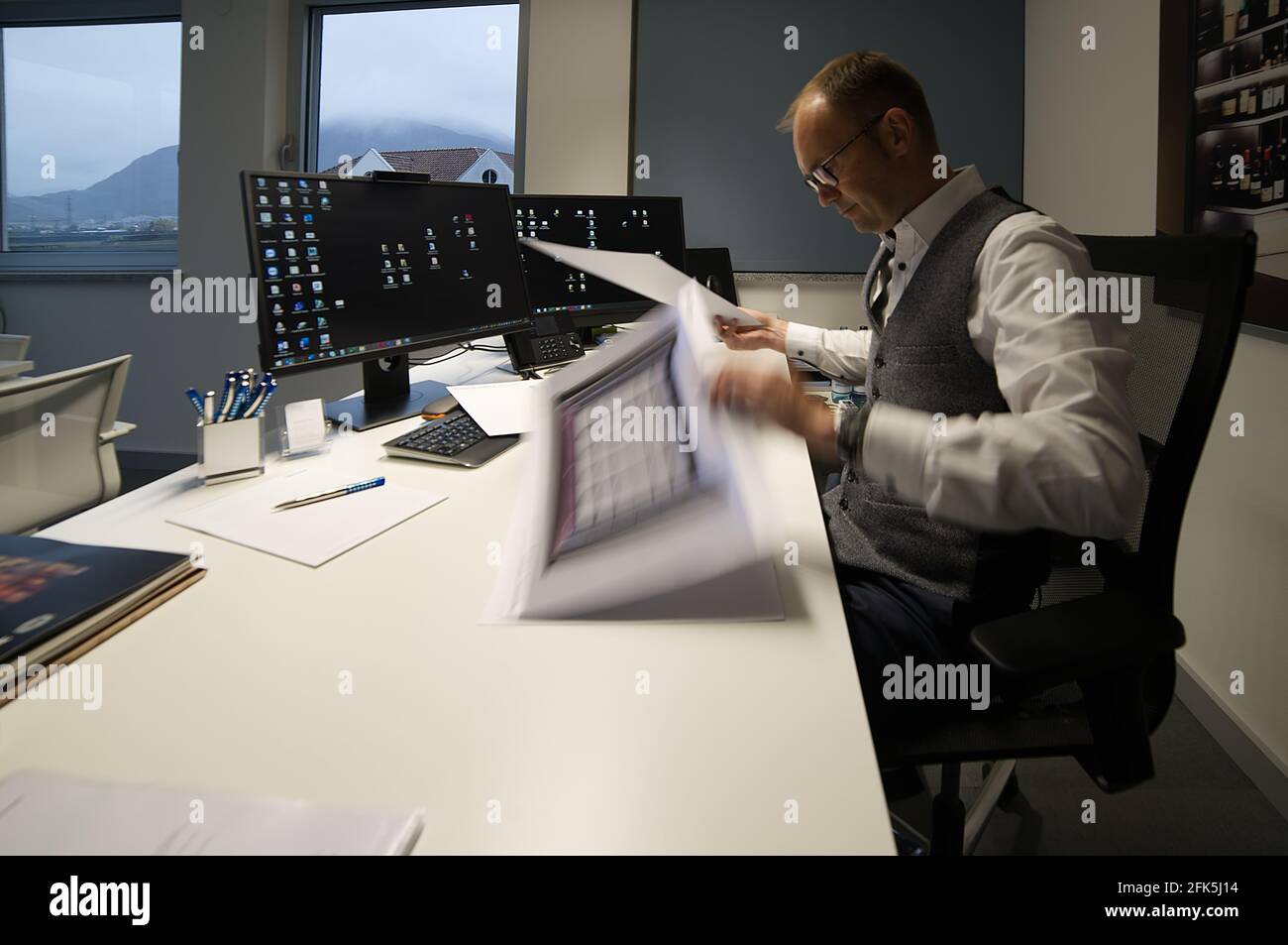 A manager - Caucasian male in his office sitting behind the desk looking at the files. Stock Photo