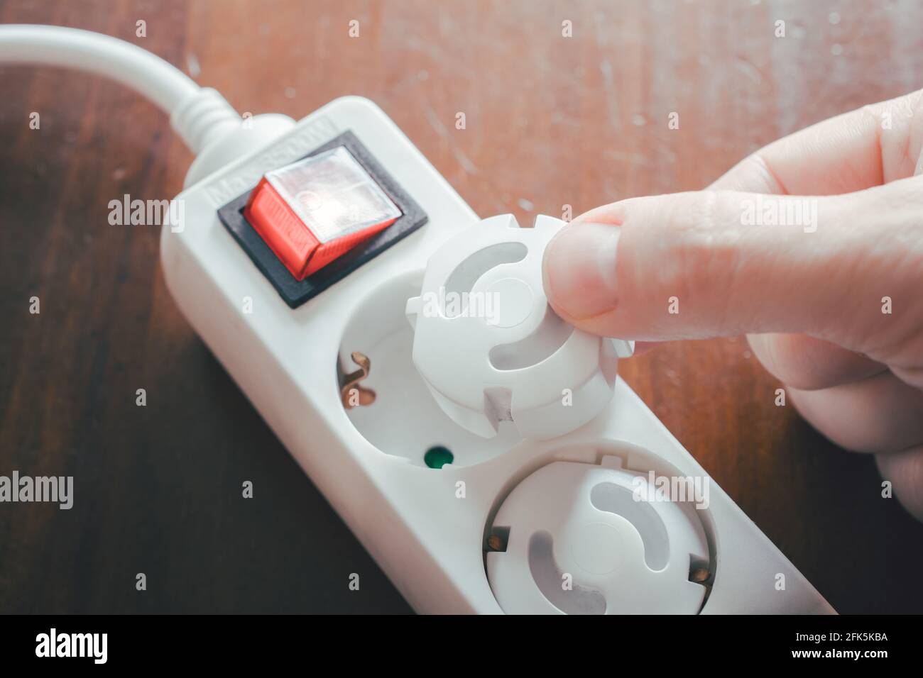 Hand Inserting Baby Safety Plugs Into Power Strip Child Safety
