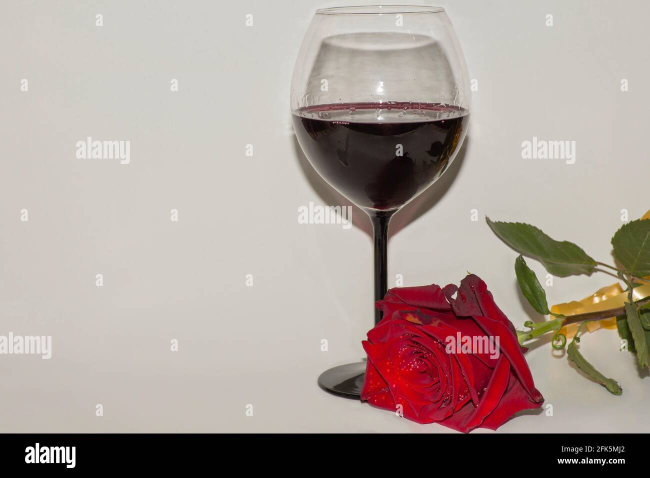Beautiful red rose and glass of red wine on white background with copy ...