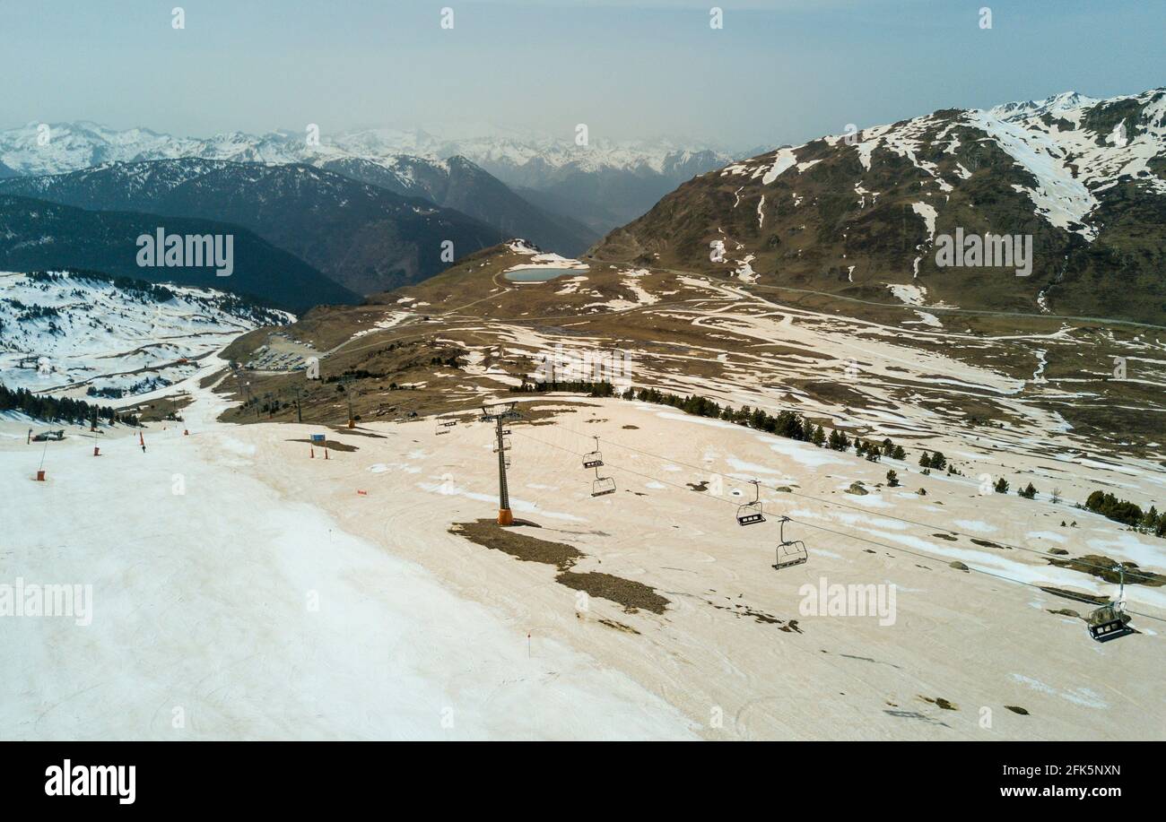 Aerial view taken from a drone, showing the orange brown coloured patches of snow below Doppelmayr chairlift systems, resulting from Sahara dust on the rocky slopes of some of the highest parts of the Pyrenees mountains in the ski resort of Baqueira in north Catalonia, Spain. © Time-Snaps Stock Photo