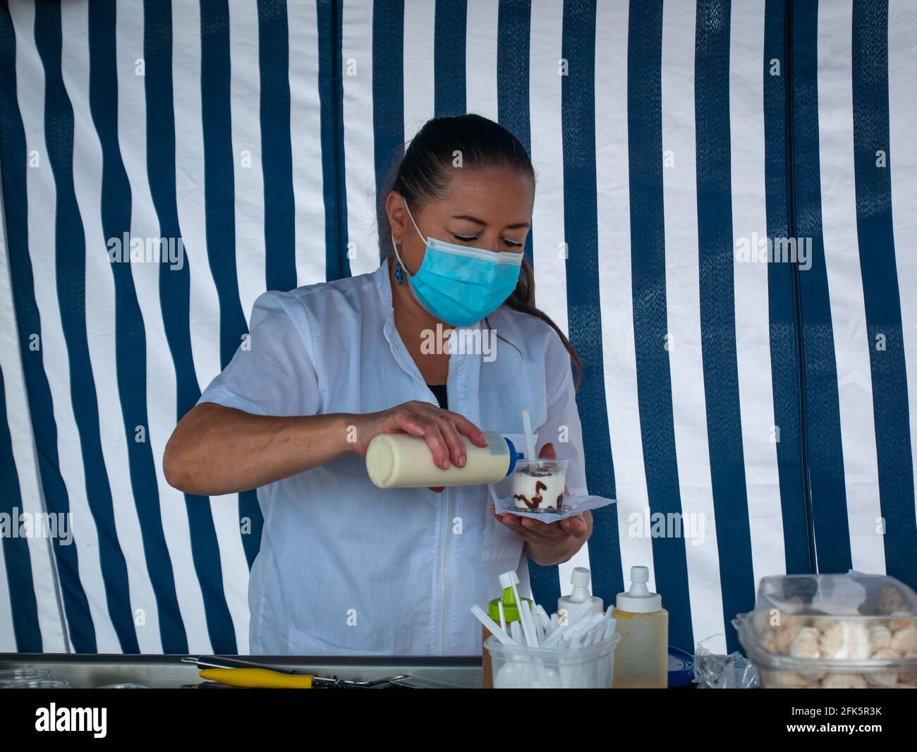 Guatapé, Antioquia, Colombia - April 4 2021: Latina Woman Serving a Creamy Dessert at her Work Stand Stock Photo