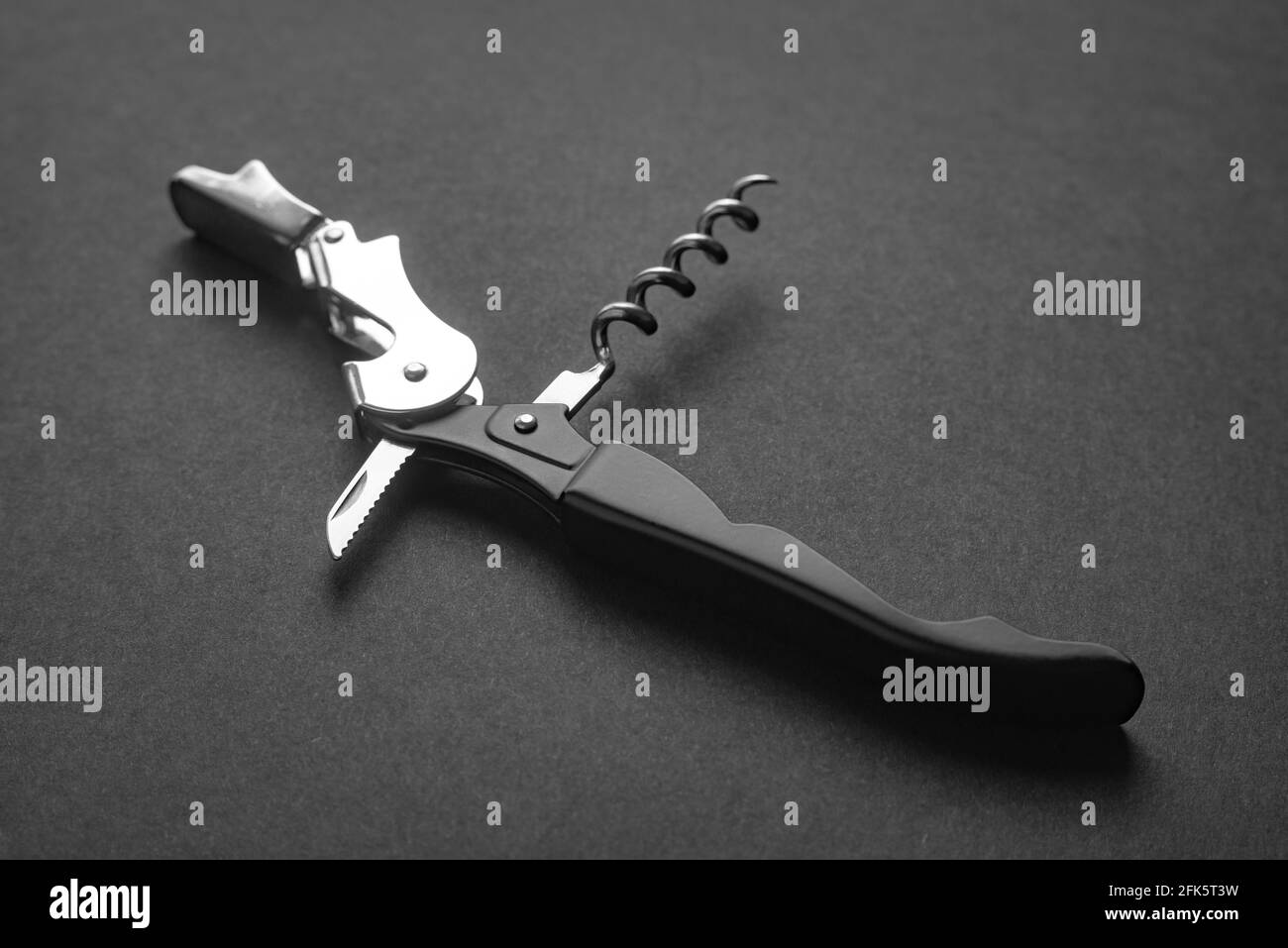 Opened sommelier knife with corkscrew and bottle opener, professional waiter knife, on black background. Stock Photo