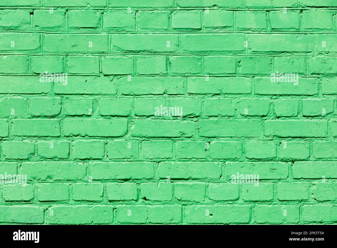 The bright texture of an old brick wall is completely painted with